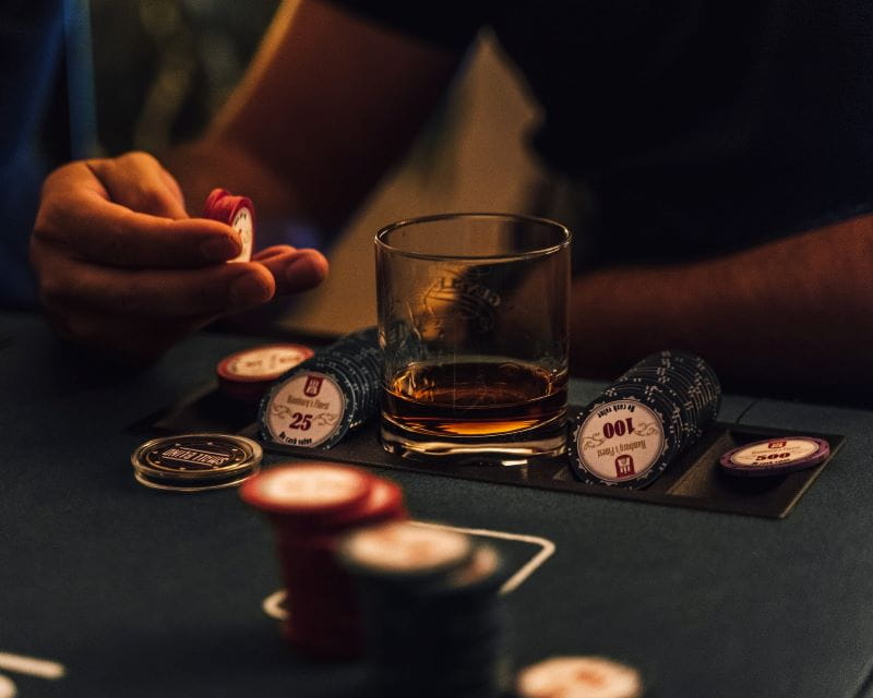 Hand, poker chips and glass of whiskey.